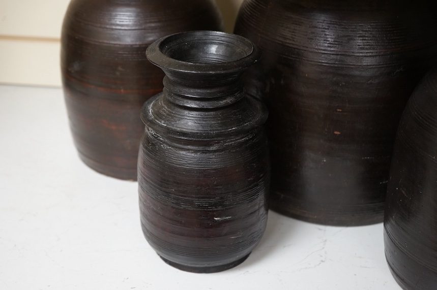 A set of six Nepali turned Himalayan hardwood pots, largest 42cm high. Condition - some breaks and repairs